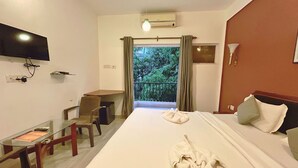 A hotel room with a bed, a desk, a chair, a TV, and a balcony with curtains. - Hotel Grand Image Inn (Calangute)