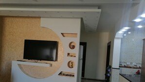 A modern living room with a built-in entertainment unit, a flat-screen TV, and a decorative wall with geometric shapes. - Petra Guests Home  (Wadi Musa)