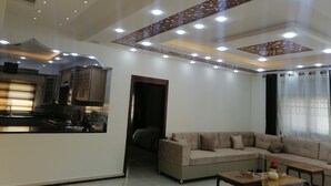 A living room with a sofa, a coffee table, and a kitchen area with cabinets and a stove. - Petra Guests Home  (Wadi Musa)