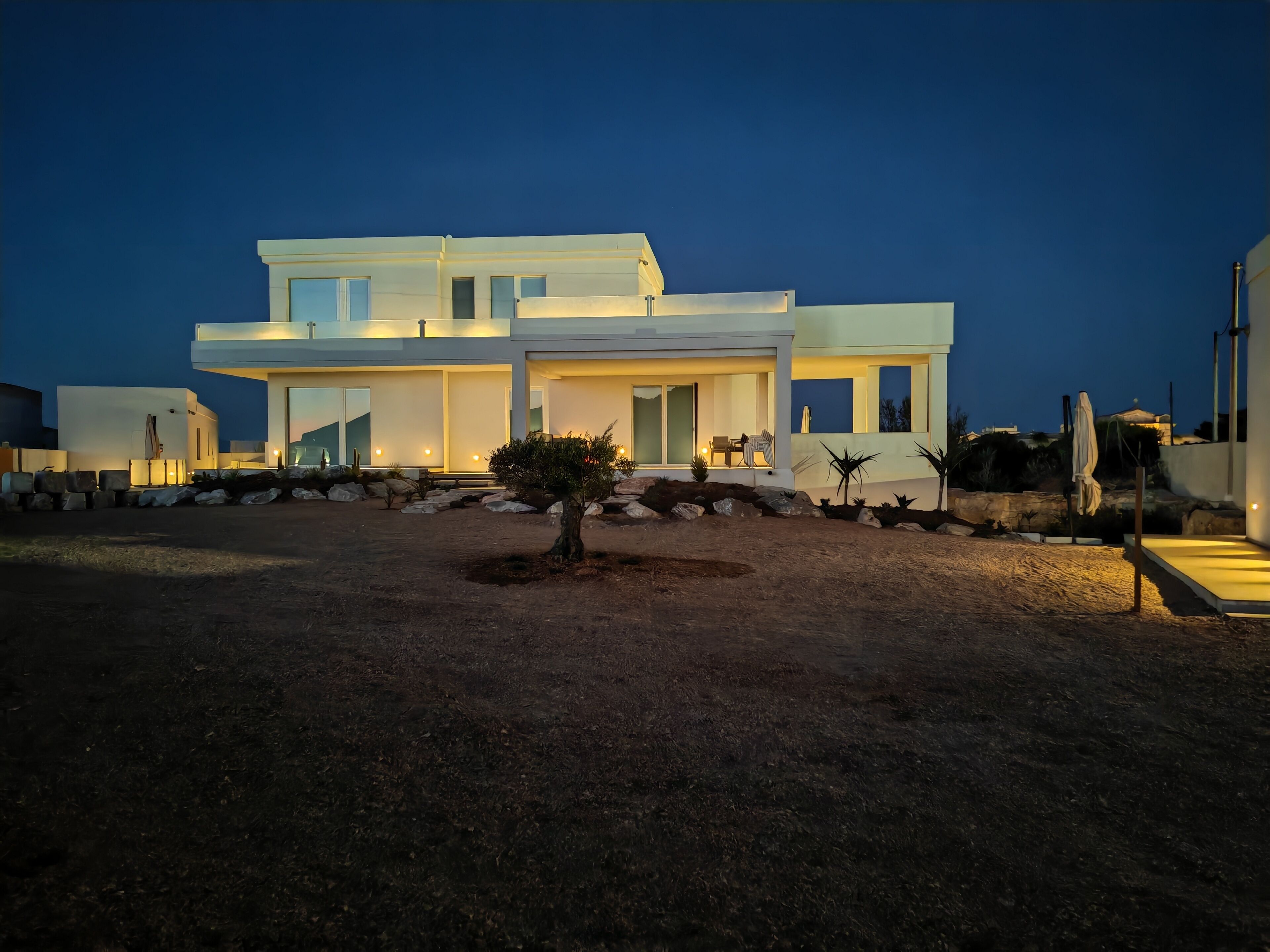 A modern two-story house with a well-lit entrance and a landscaped garden.