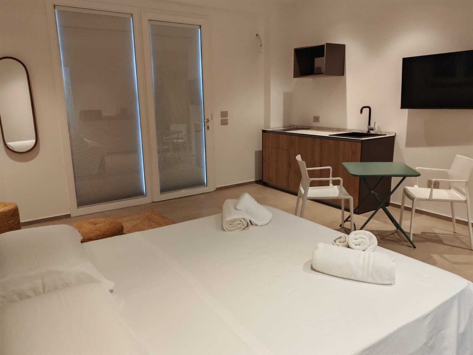 Ein Hotelzimmer mit einem Bett, einem kleinen Tisch, zwei Stühlen, einem Fernseher und einer Küchenzeile.