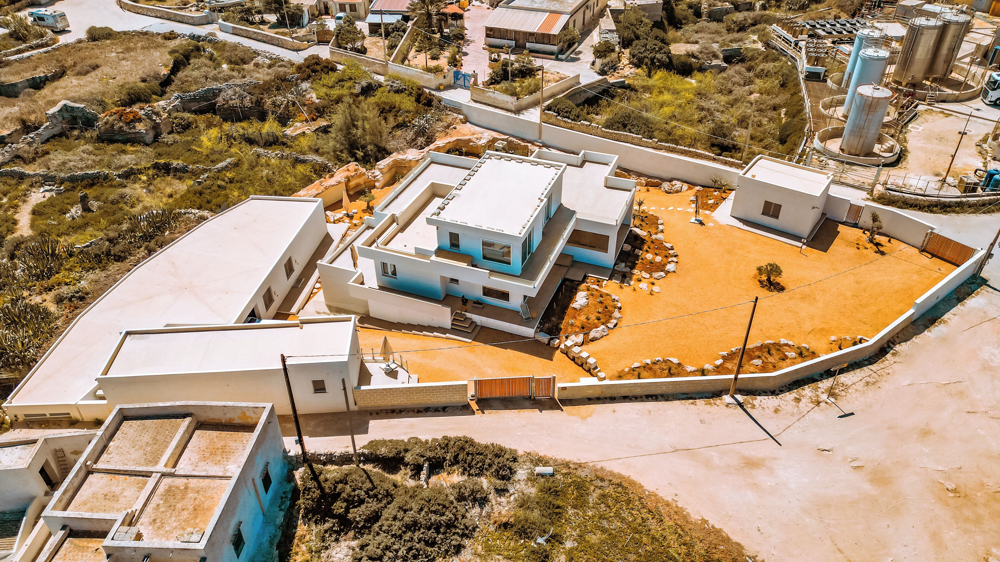 Vista aérea de un área residencial con casas modernas, un patio central y vegetación circundante.