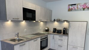 Een moderne keuken met een magnetron, oven, spoelbak en koffiezetapparaat.