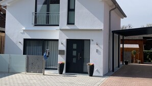 Een gebouw met twee verdiepingen, een plat dak, een balkon op de bovenverdieping en een garagepoort.