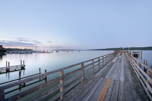 Un muelle de madera que se adentra en aguas tranquilas, con barcos amarrados a la izquierda.
