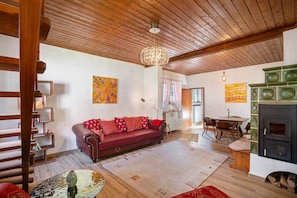 Una sala de estar acogedora con techo de madera, un sofá rojo, una mesa de comedor y una chimenea.