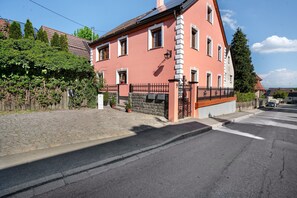 A pink building with a stone wall, a black metal fence, and a cobblestone path. - Holiday Home 'Ludava' with Wi-Fi (Diessen)