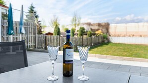 A patio table with a bottle of wine and two glasses.