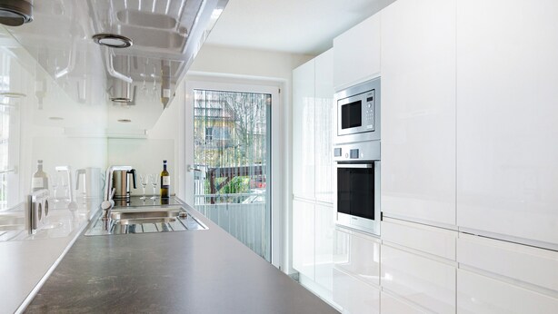 A modern kitchen with stainless steel appliances, a large countertop, and a view through a glass door.