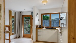 A modern kitchen with a wooden countertop, white cabinets, and a window overlooking a garden. - Apartment 'Würtenberger 68 Qm' with Private Terrace, Private Garden and Wi-Fi (Öhningen)