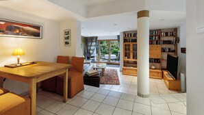 A spacious living area with a dining table, sofas, a coffee table, a bookshelf, and a television. - Apartment 'Würtenberger 68 Qm' with Private Terrace, Private Garden and Wi-Fi (Öhningen)