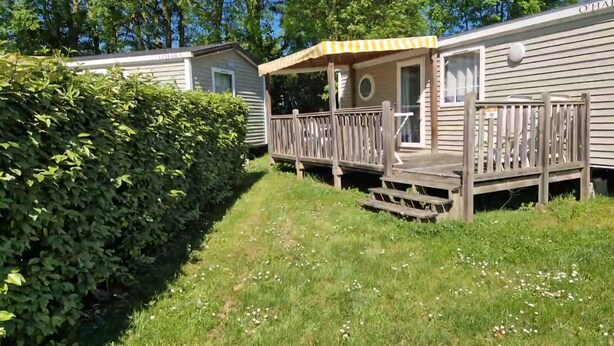 Une maison mobile dotée d’une terrasse en bois et d’un porche abrité.
