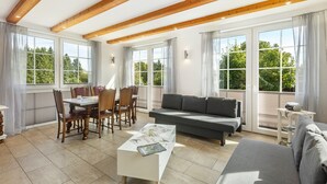 A spacious living area with a dining table, sofa, and large windows offering a view of greenery. - Apartment 'Nr 4' with Shared Garden and Wi-Fi (Kirchhundem)