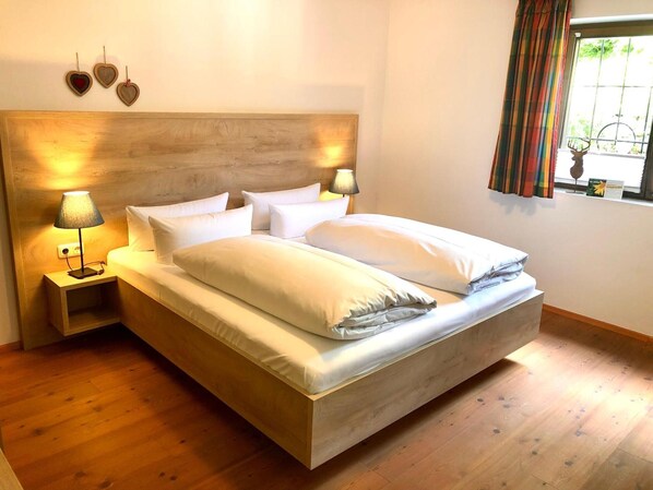 A neatly made bed with white linens, two bedside lamps, and a wooden headboard.