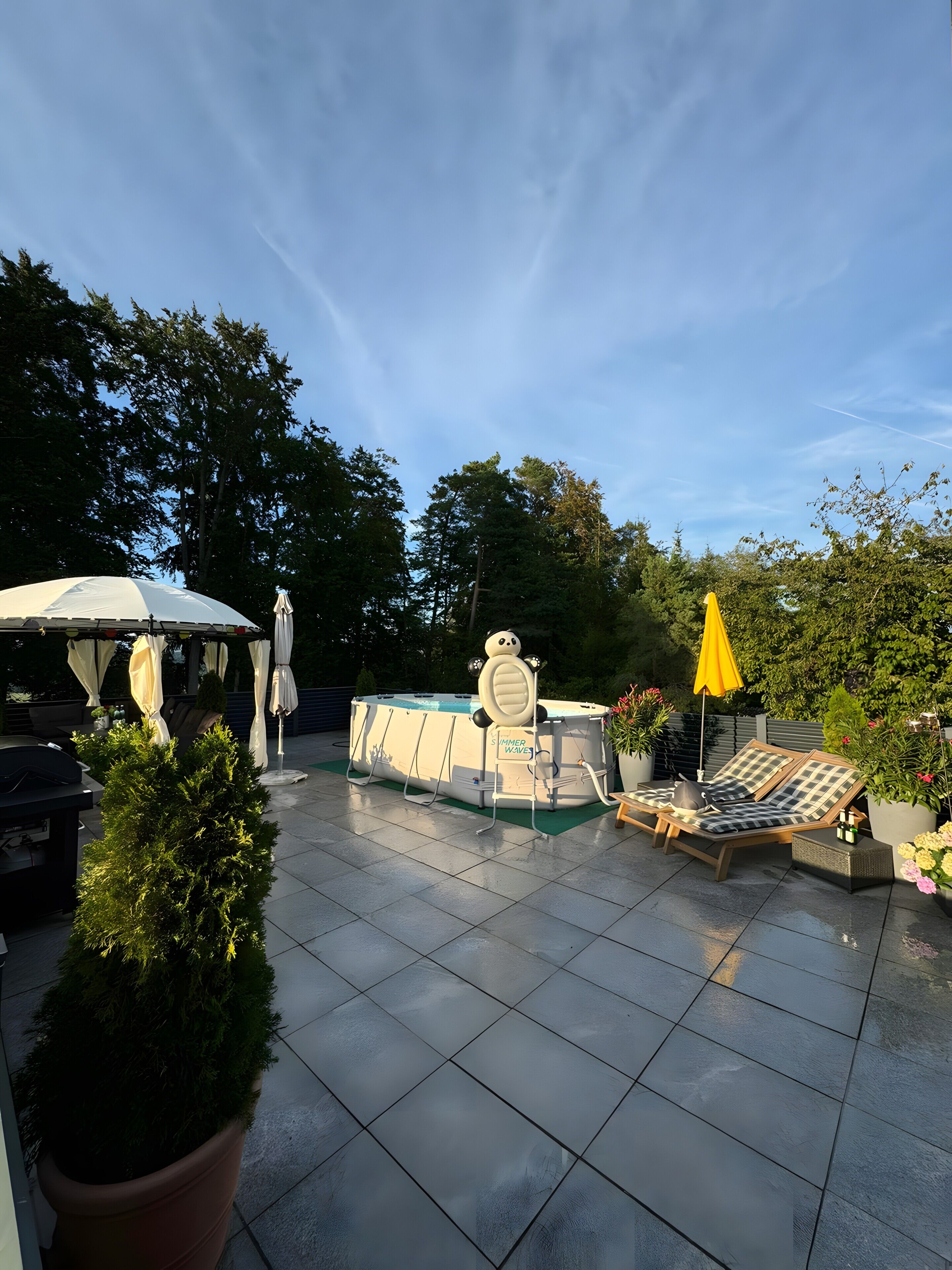 Ein Poolbereich mit Whirlpool, Liegestühlen und Sonnenschirmen.