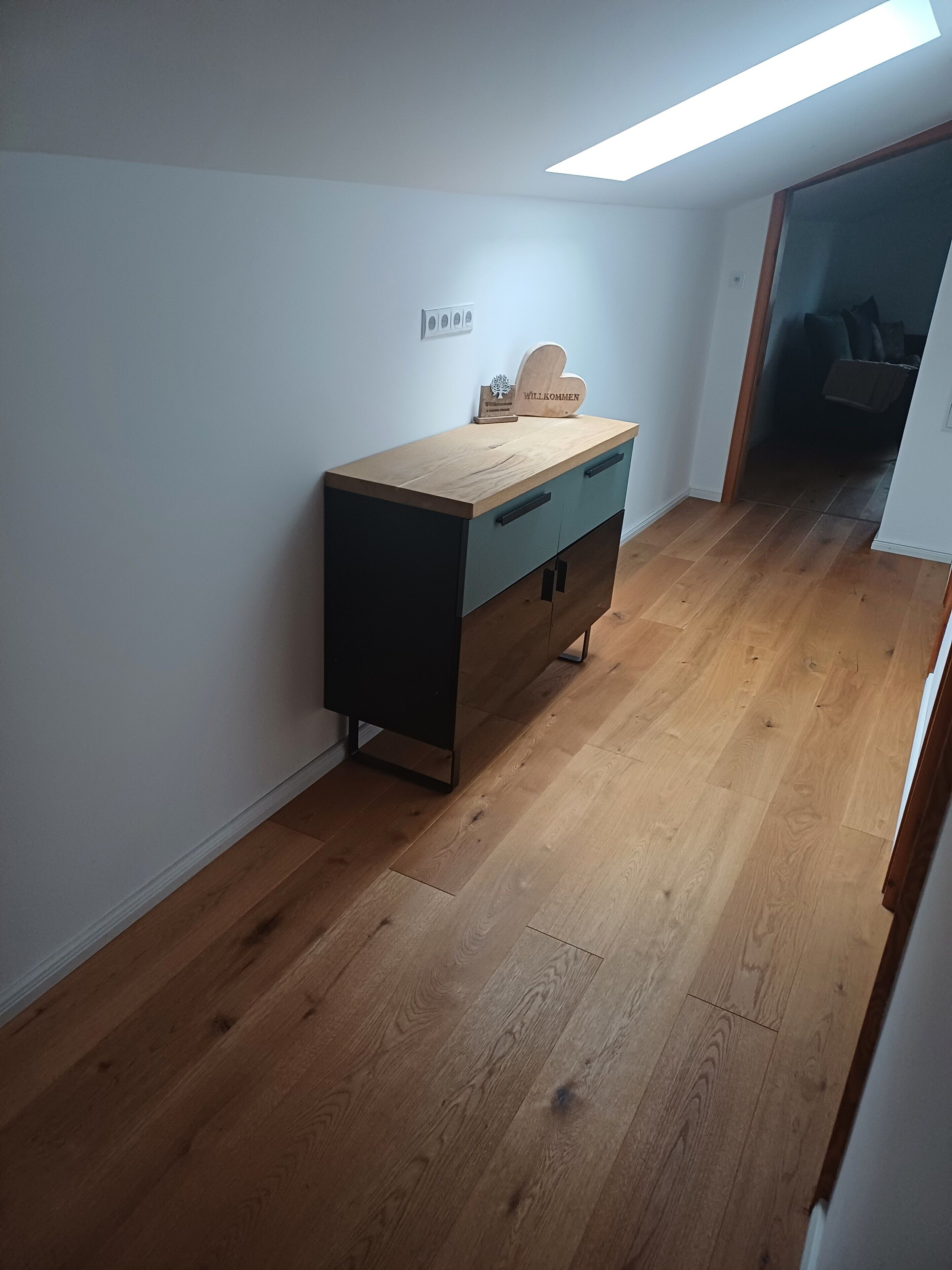 Une pièce avec un bureau en bois, un tiroir bleu et un luminaire au plafond.