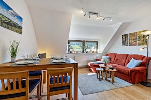 Ein Essbereich mit Holztisch, Stühlen und einem roten Sofa.