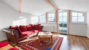 Un salon spacieux avec un canapé en cuir, une table basse en bois et une grande fenêtre donnant sur un paysage agréable.