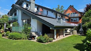 Een modern huis met een schuin dak, een overdekt terras en een verzorgd gazon.