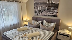 Een slaapkamer met een bed, nachtkastjes, een vloerkleed en een aan de muur hangend schilderij.