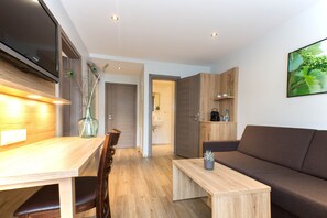 Un espacio habitable moderno con una mesa de comedor de madera, un sofá y un televisor montado en la pared.