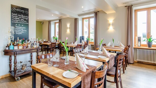 Een restaurant met houten tafels, stoelen en een krijtbordmenu.