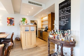 Un restaurante con mobiliario de madera, una zona de bar con botellas y un menú en una pizarra.