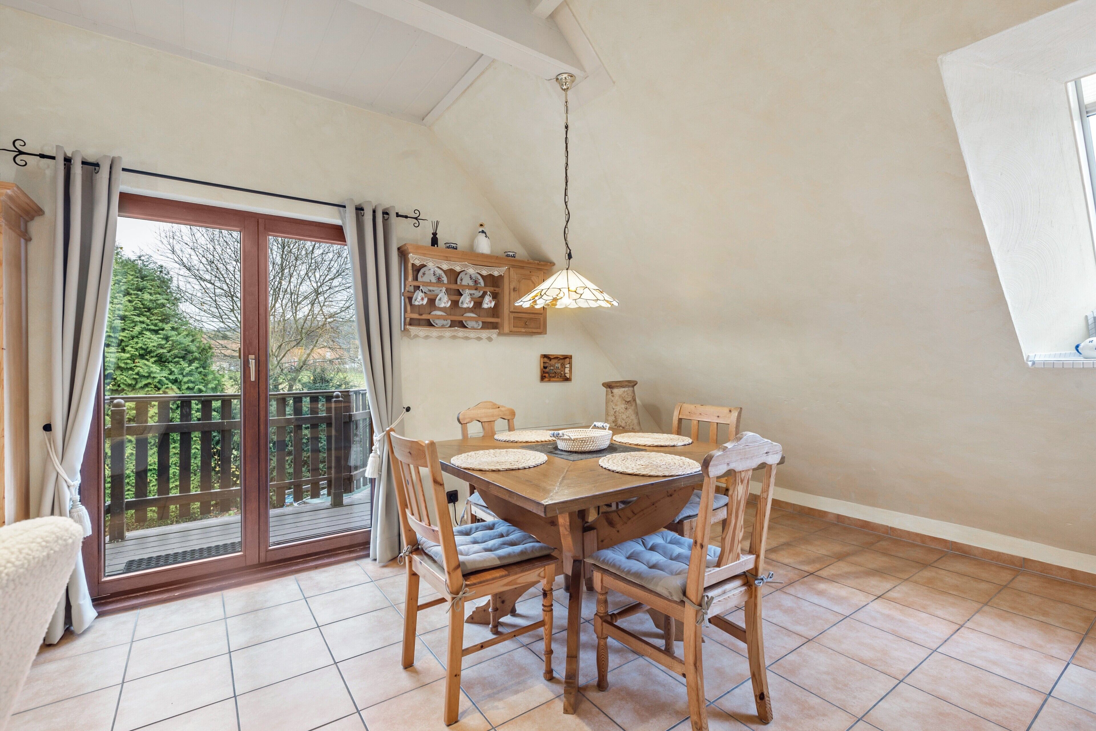 Un espace repas comprenant une table en bois, des chaises et un luminaire suspendu.