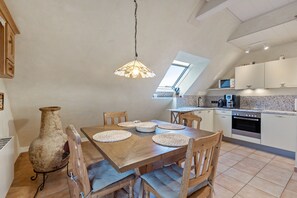 Un espace repas comprenant une table en bois, des chaises et un luminaire suspendu.