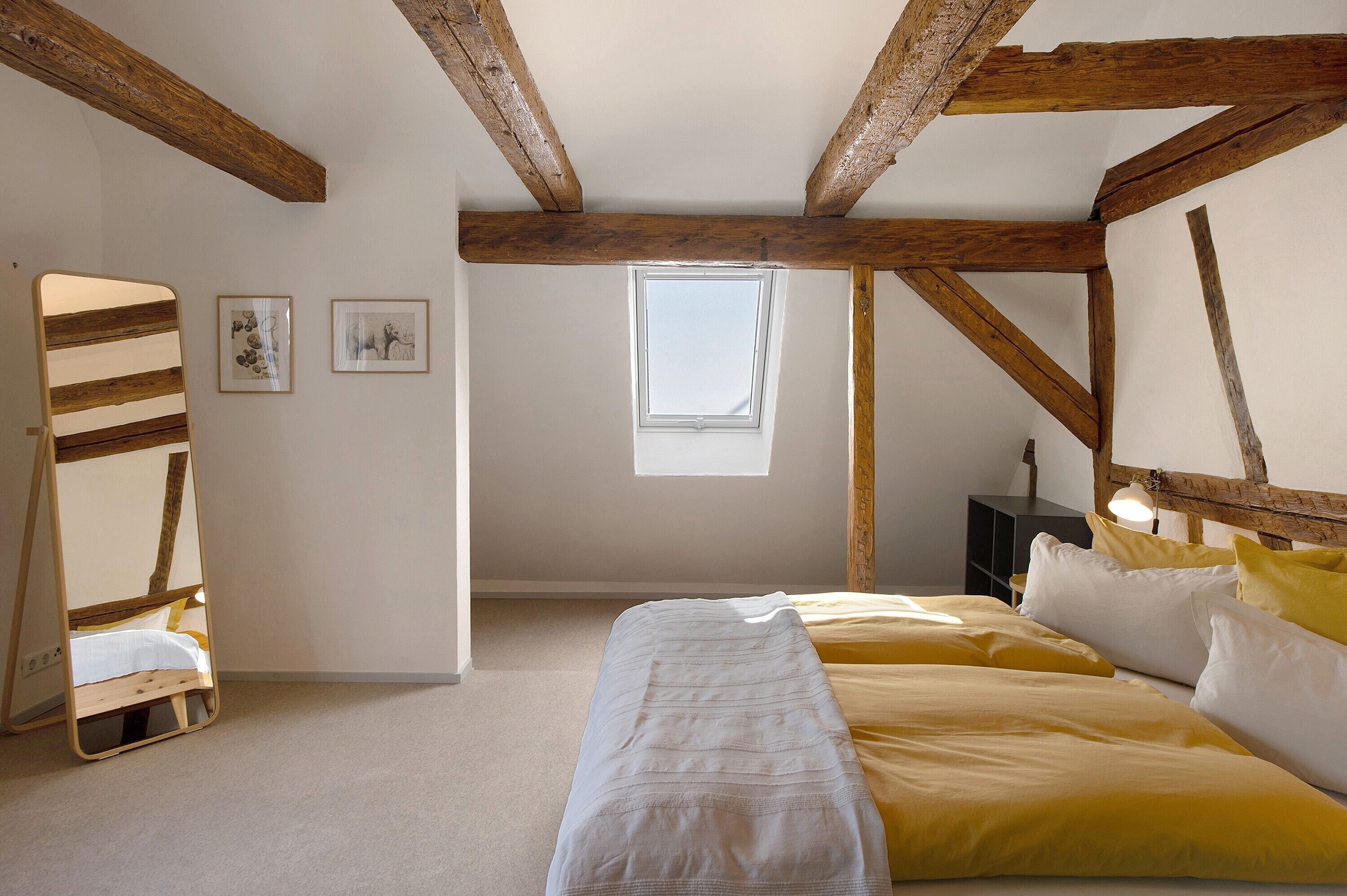 Ein Schlafzimmer mit einem Hochbett, einem Oberlicht und einer Holzbalkendecke.
