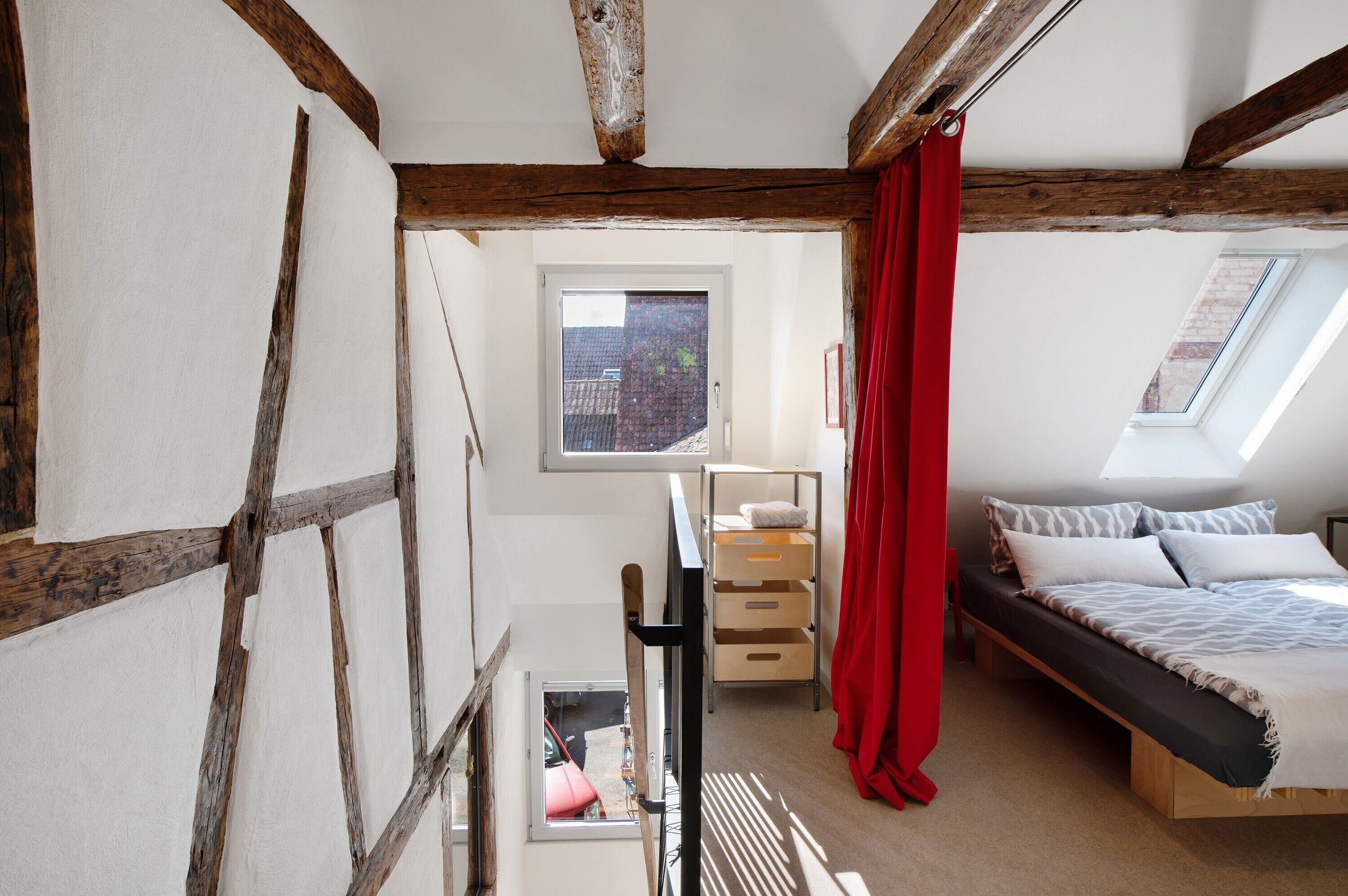 A bedroom with a loft bed, a window, and a skylight.