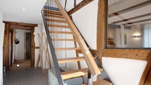 Una escalera de madera con diseño moderno, una pared blanca y una puerta visible que da a otra habitación.