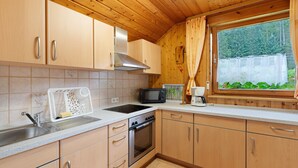 Una cocina con armarios de madera, un microondas, una estufa y una ventana con cortinas.