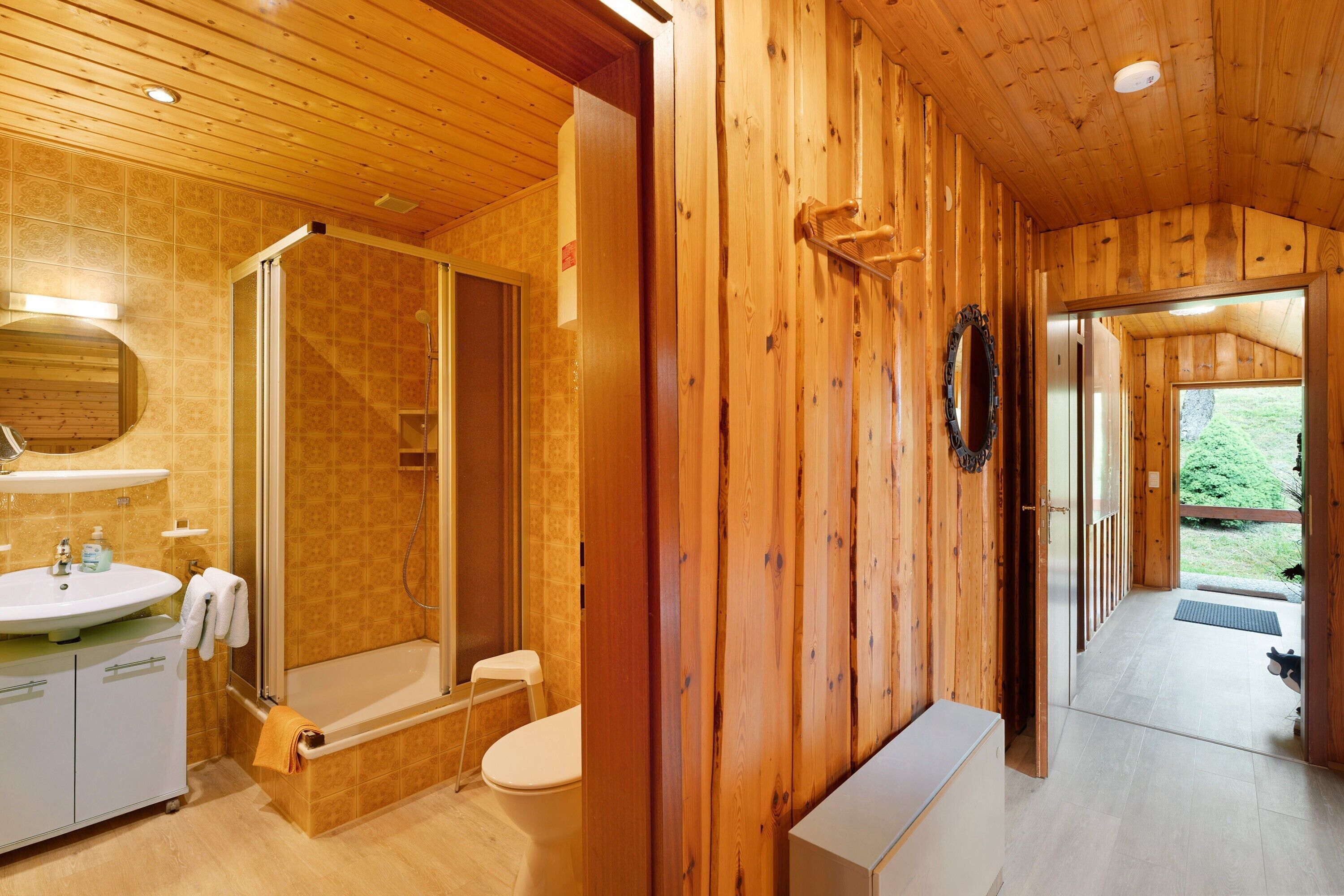 A wooden interior with a bathroom including a sink, toilet, and shower.