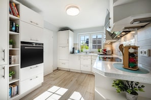 Eine moderne Küche mit weißen Schränken, einem eingebauten Backofen und einem Fenster für natürliches Licht.