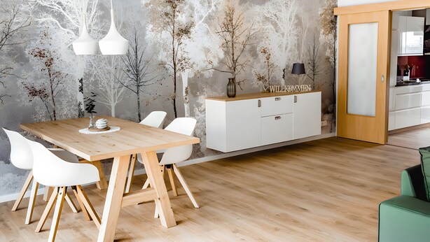 A modern dining area with a wooden table, white chairs, pendant lights, and a white cabinet. - Holiday Apartment 'Waldfeeling' with Private Terrace and Wi-Fi (Brilon)