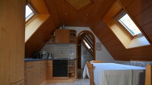 Une cuisine compacte avec des meubles en bois, une table à manger et deux fenêtres de toit.