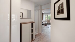 Ein Flur mit einem Holzschrank, einem gerahmten Bild an der Wand und einem Blick in einen Essbereich mit Tisch und Stühlen.