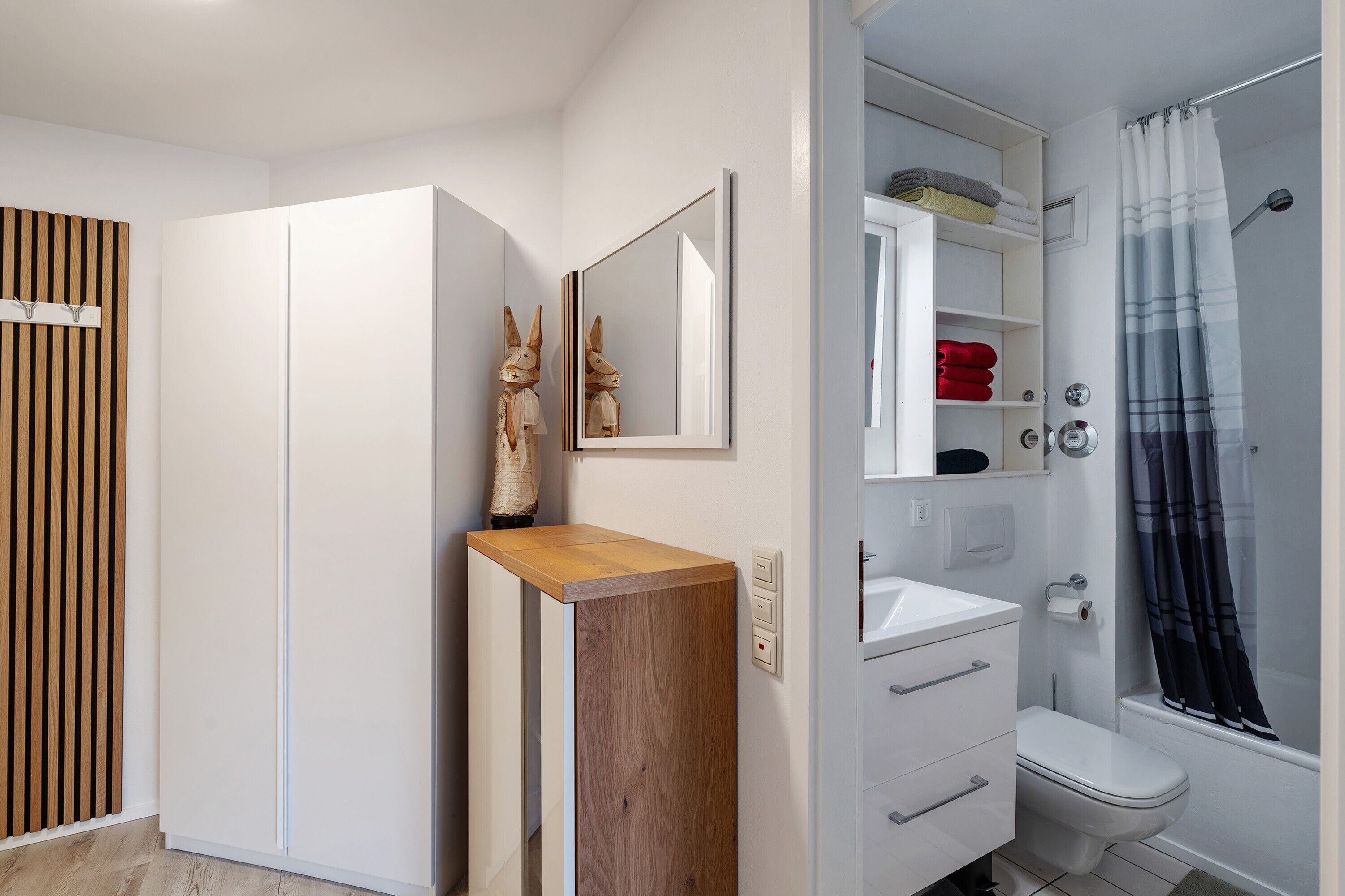 Un baño moderno con lavamanos, inodoro y zona de ducha blancos.