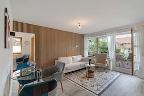 A modern living room with a sofa, chairs, a glass table, and a patterned rug.
