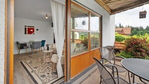 Ein Zimmer mit einer großen Schiebeglastür, die auf eine Terrasse im Freien führt.
