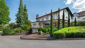 A two-story house with a balcony, surrounded by greenery and a driveway. - Apartment 'Weinbergsuite' with Private Terrace, Balcony and Wi-Fi (Kappelrodeck)