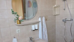 Ein Badezimmer mit Waschbecken, Spiegel, Dusche und Handtuchhalter.