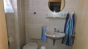 A small bathroom with a toilet, sink, and shower.