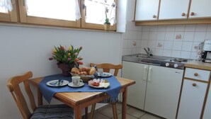 A kitchen with a dining table set for two, a sink, and a stove.