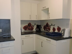 A kitchen with white cabinets, a black countertop, and a coffee maker.