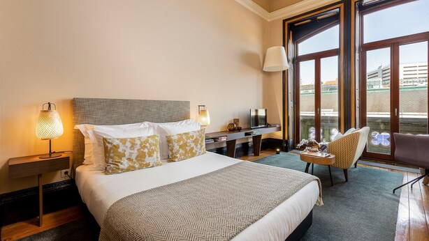 Een hotelkamer met een groot bed, een bureau, een stoel en een televisie.