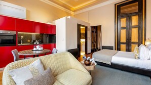 Een hotelkamer met een kitchenette, een bank, een bed en een tafeltje.