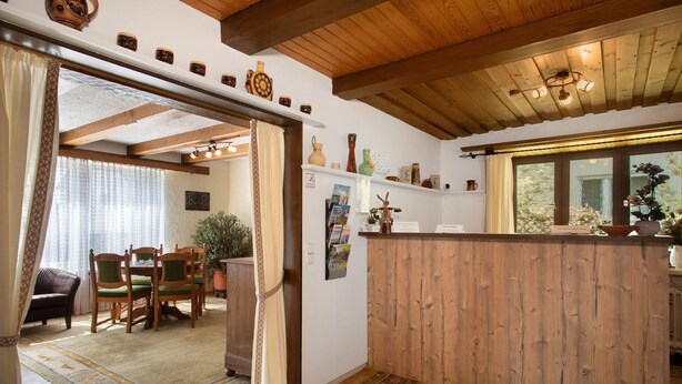 A wooden interior with a dining area, a kitchen counter, and a view through a window.