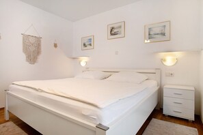 Une chambre à coucher avec un lit, des tables de chevet, des lampes fixées au mur et des tableaux encadrés.